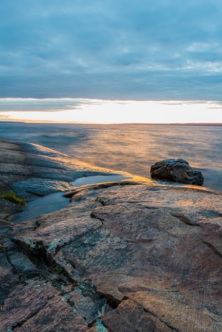 Image of sunset over lake and rock shoreline
