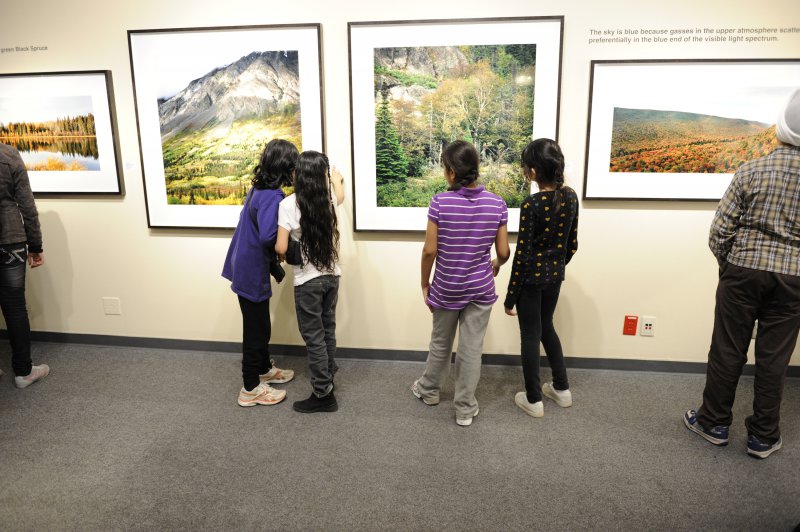 Elementary school students examine photographs in the Travelling Exhibition and Learning Experience
