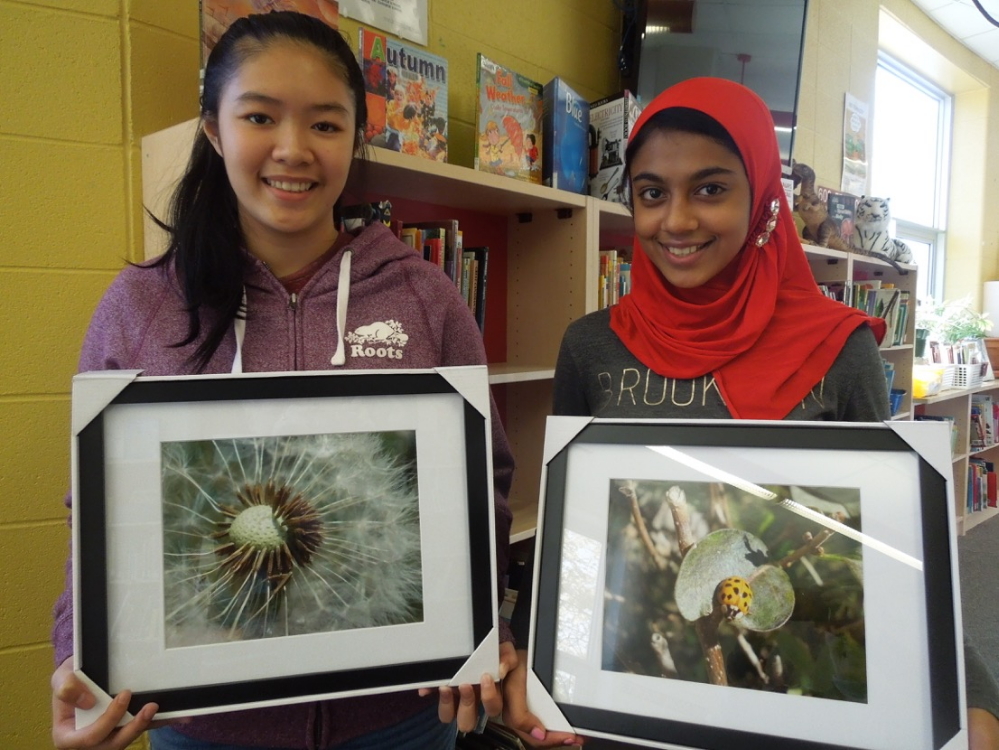 Image of two students holding framed photos
