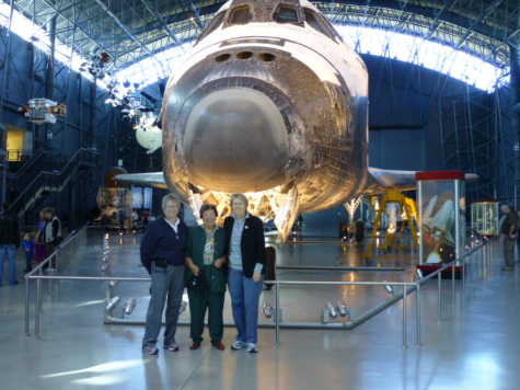 three women stand in front of old space shuttle